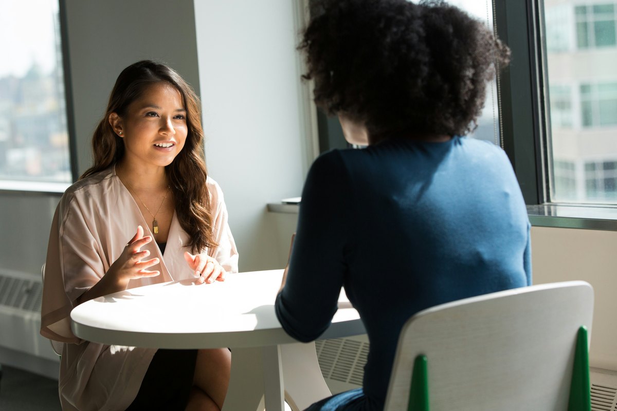 Two clinicians seated across from each other in conversation in a comfortable professional setting